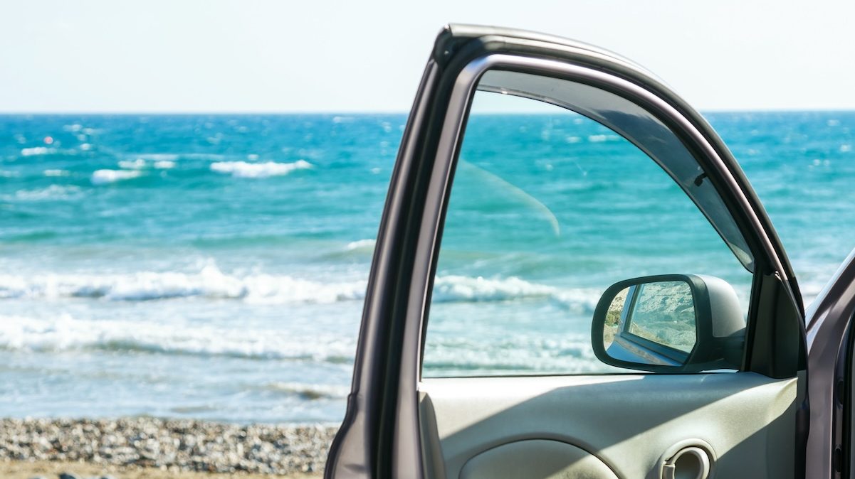 Car door and beautiful seascape. Close up of door window with sea in background.